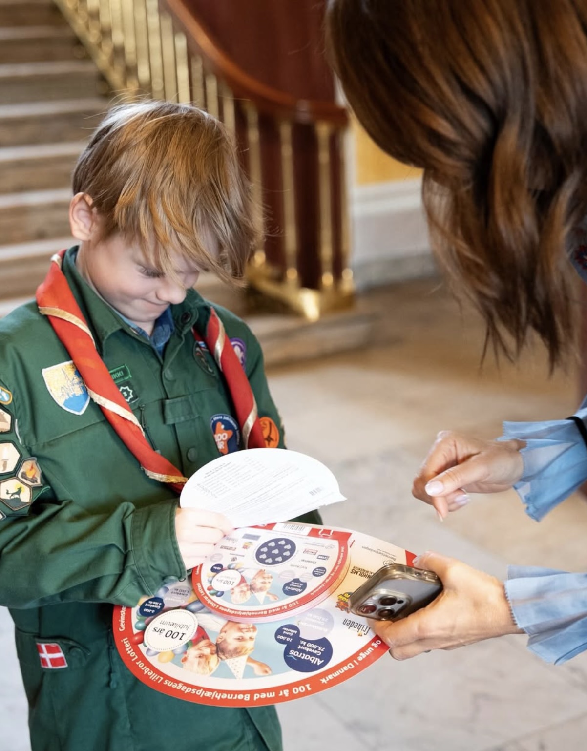 En gutt i speideruniform viser lodd til dronning Mary