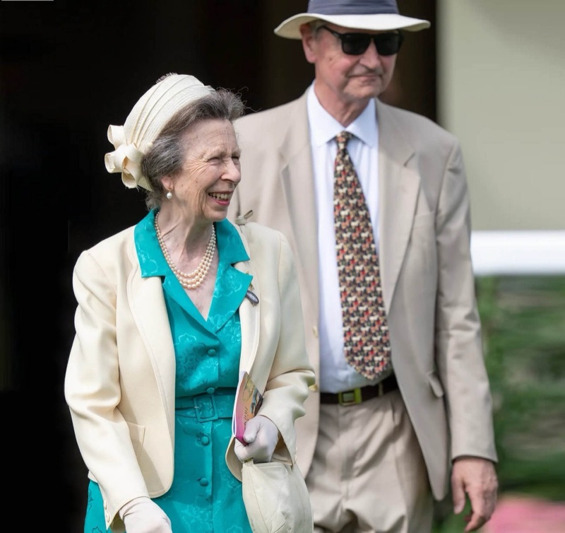 Prinsesse Anne smiler, med Sir Tim Laurence bak seg