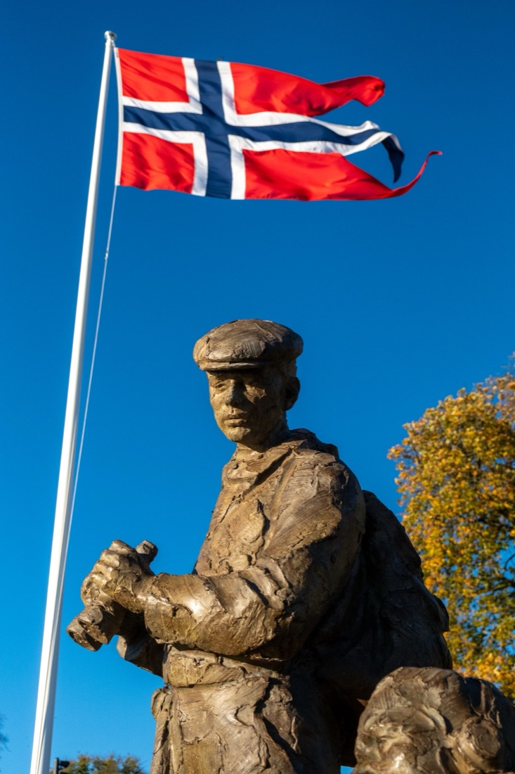 Nærbilde av kystobservatøren i skulpturen, med det norske flagget vaiende over