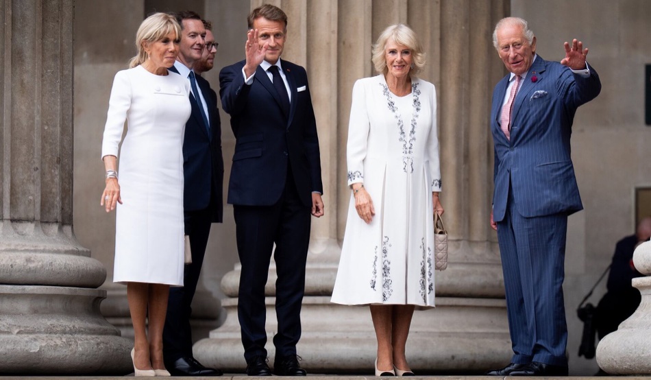 Brigitte Macron, President Macron, Queen Camilla and King Charles stand between the columns on the steps of the British Museum, the King and the President waving