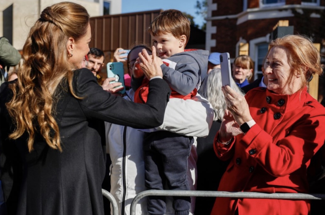 Prinsessen av Wales hilser på et lite barn som holdes opp over sperringen utenfor The Commons
