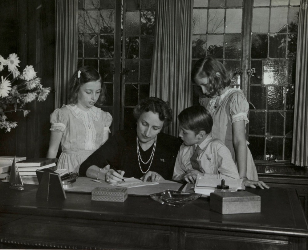 Crown Princess Märtha and the three children sit around a table writing Christmas cards
