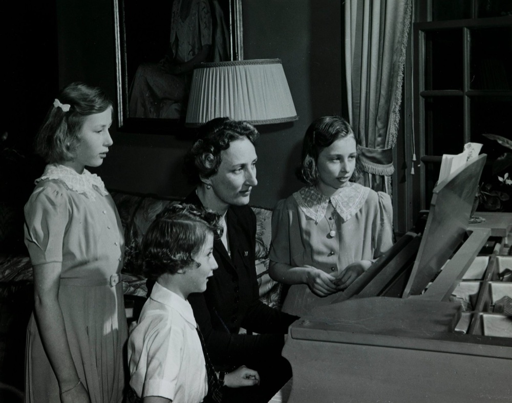 Crown Princess Märtha with Ragnhild, Astrid and Harald gathered around a piano