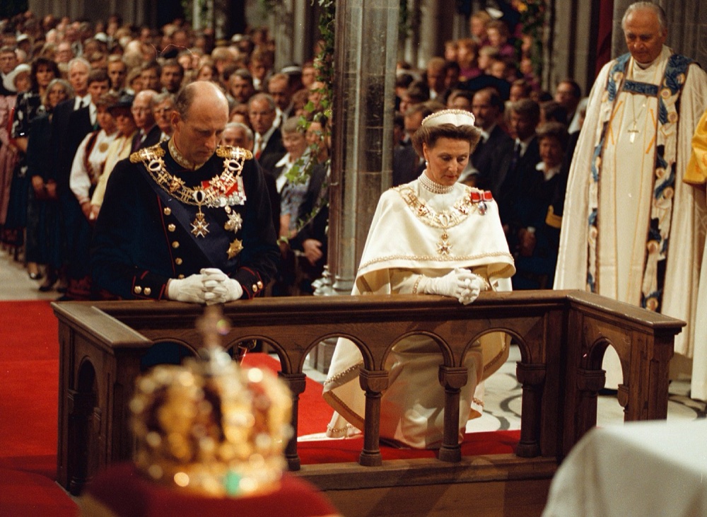 Kong Harald og dronning Sonja kneler ved alteret i Nidarosdomen med kronene stilt fram