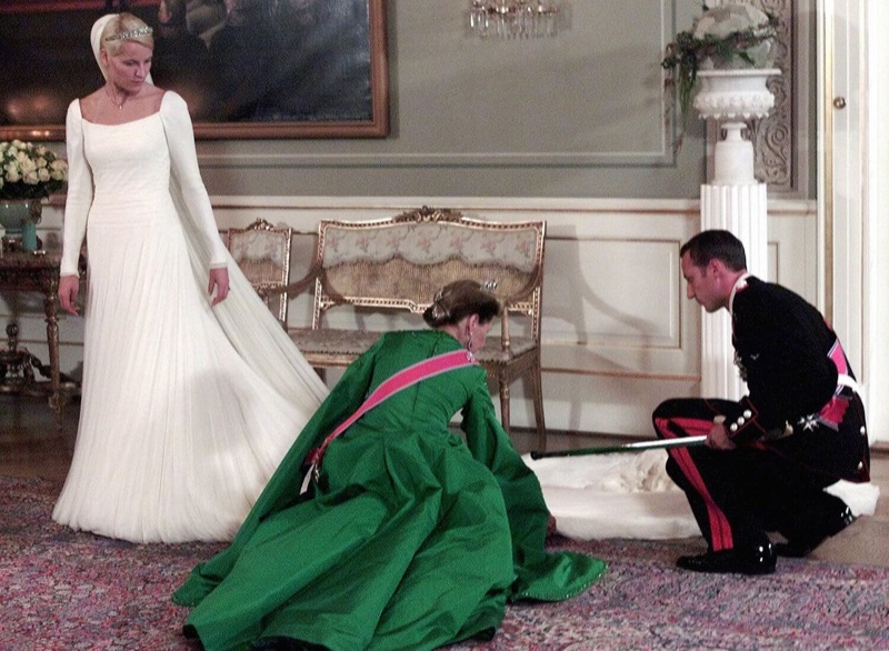 Dronning Sonja i grønn kjole ordner brudekjolens slep