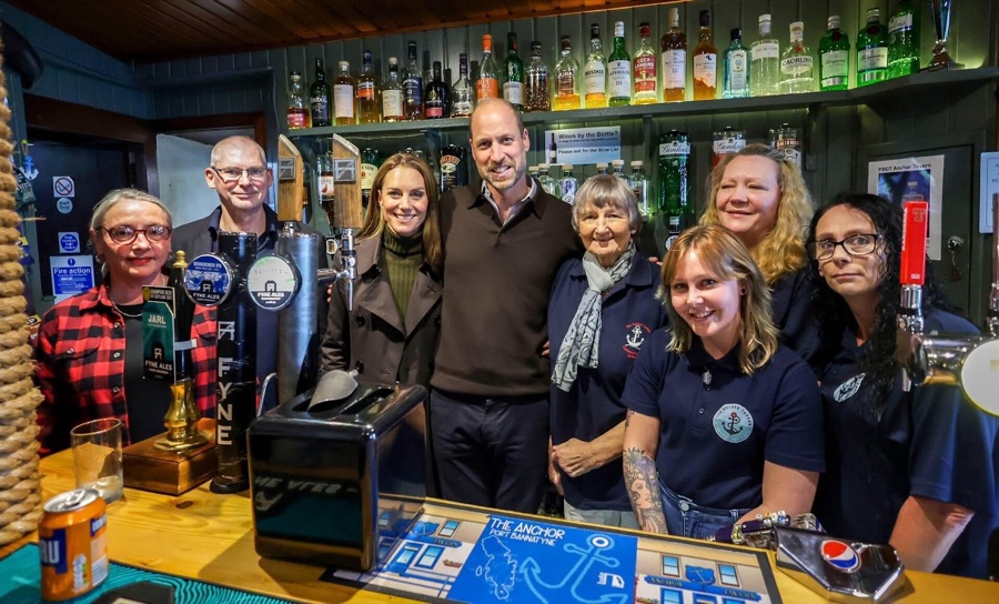 Prince William and Princess Catherine stand behind the bar with six members of staff at The Anchor pub