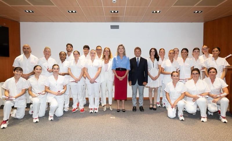 Gruppebilde av prinsesse Caroline sammen med hele kullet i hvite uniformer, med diplomene i hendene