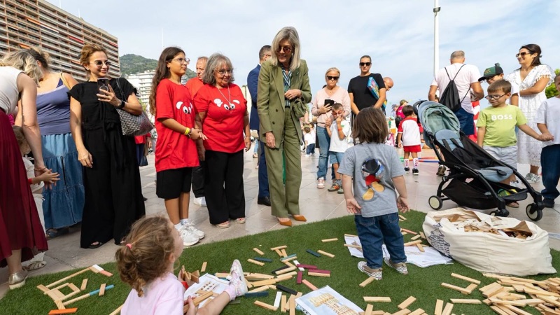 Princess Caroline watches children building with wooden blocks on a patch of artificial grass