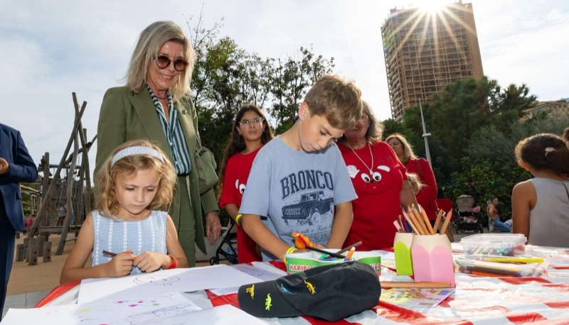 Princess Caroline watches as two children draw at a table with coloured pencils