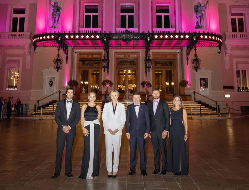 Princess Charlène and five others lined up in front of the casino in Monte-Carlo, bathed in pink light