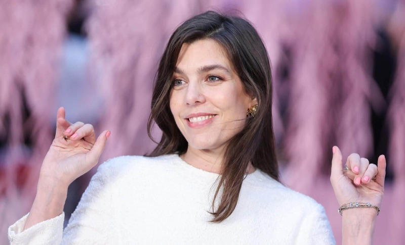 Charlotte Casiraghi smiler foran en rosa bakgrunn