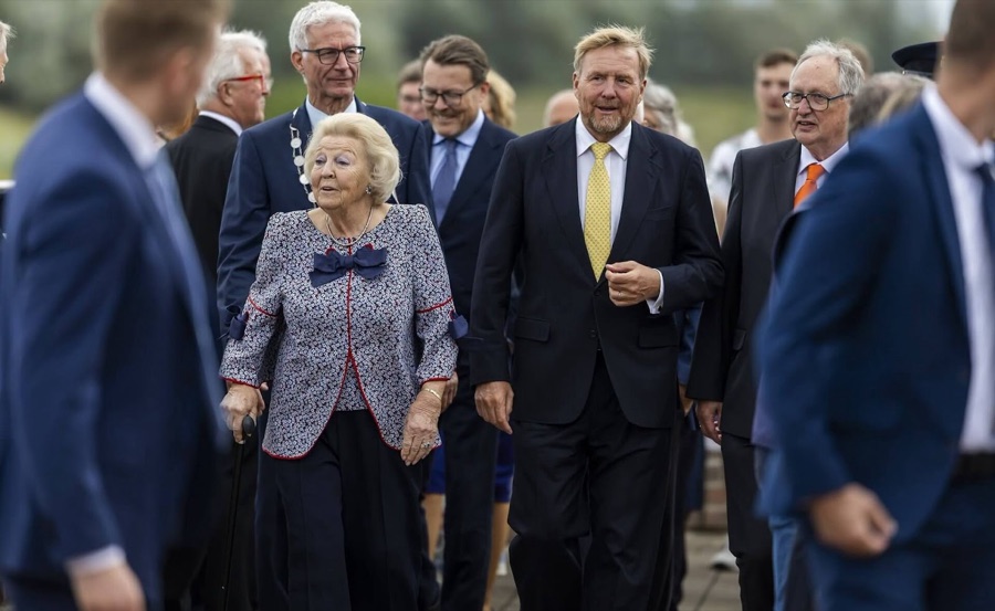 Princess Beatrix, using a walking stick, walks with King Willem-Alexander, Prince Constantijn and local representatives wearing chains of office