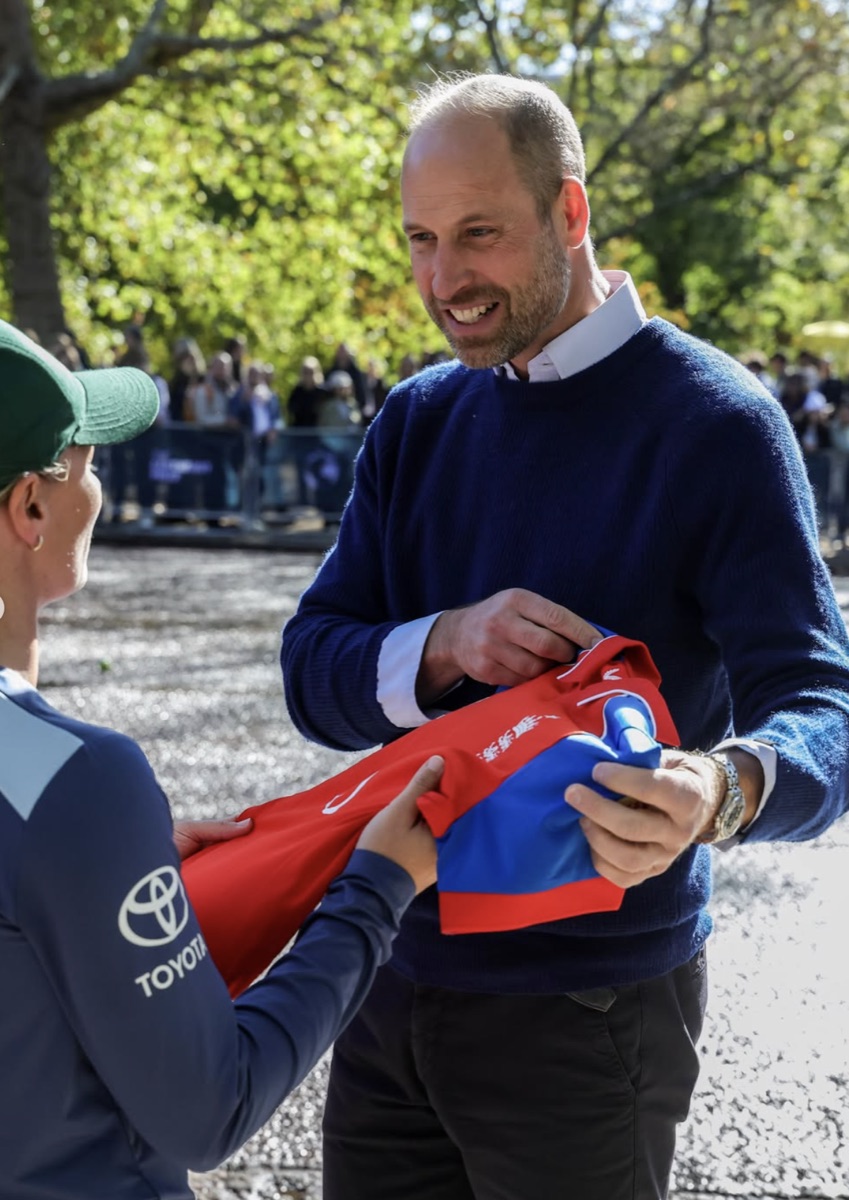 Prins William smiler mens han signerer en drakt