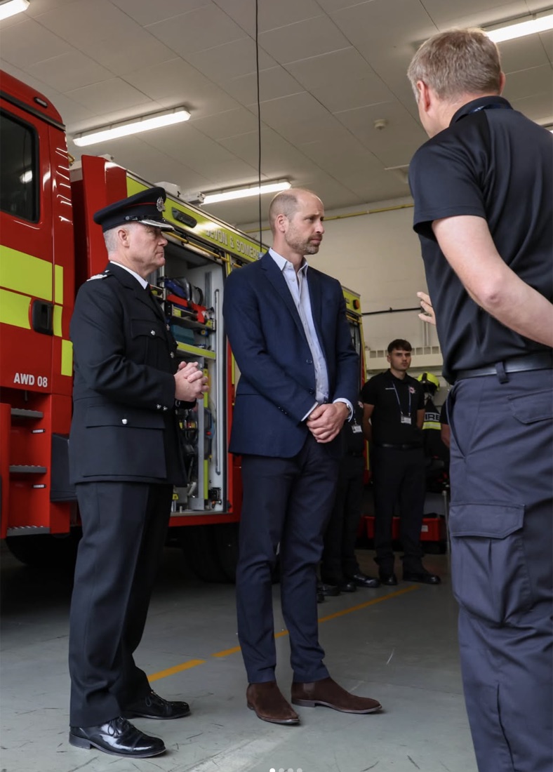 Prins William sammen med en brannsjef i uniform ved siden av en brannbil inne i vognhallen