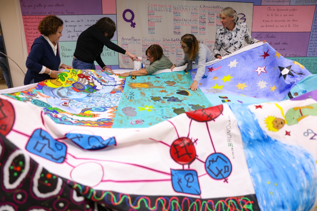 Volunteers unfolding a large colourful patchwork quilt with names and drawings made by people living with HIV