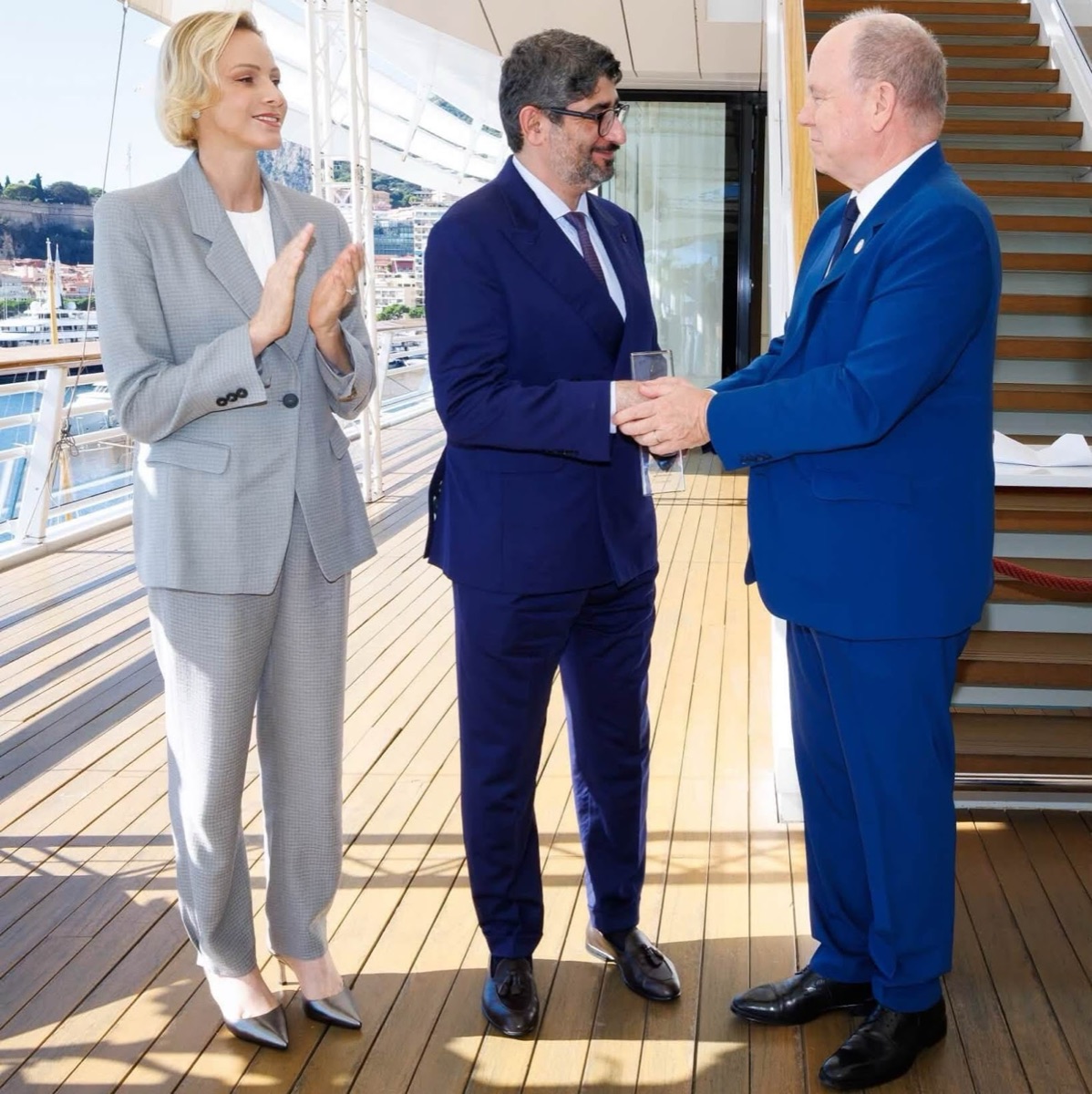 Fyrst Albert rekker prisen til representanten for MBRGI mens fyrstinne Charlène applauderer på dekket i Yacht Club de Monaco