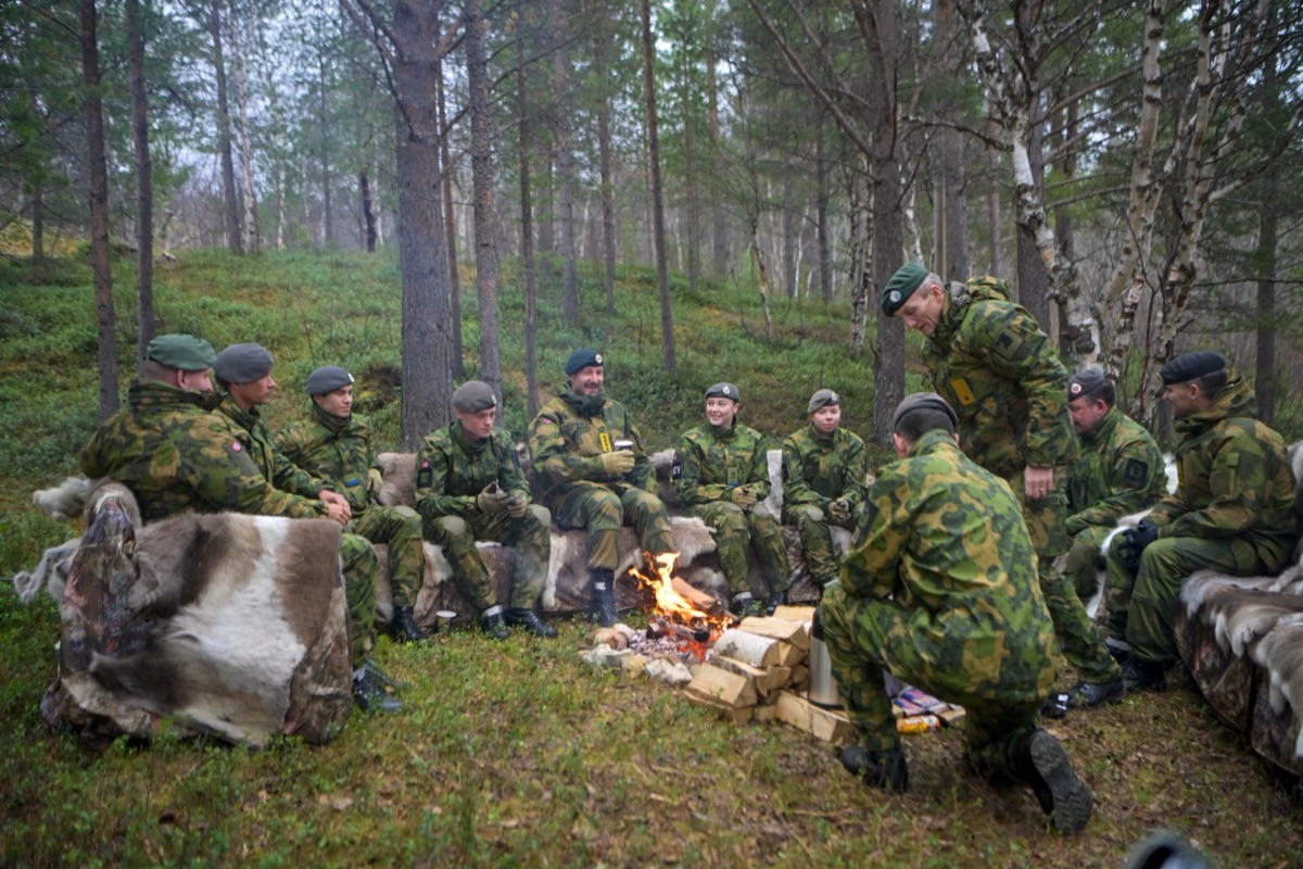 Soldater sitter samlet rundt et bål i skogen