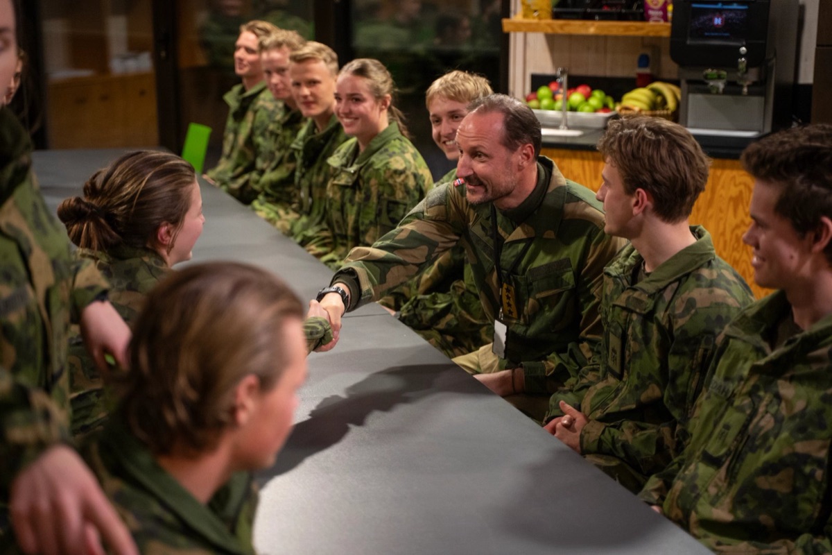Kongen håndhilser på soldater langs et bord i messa
