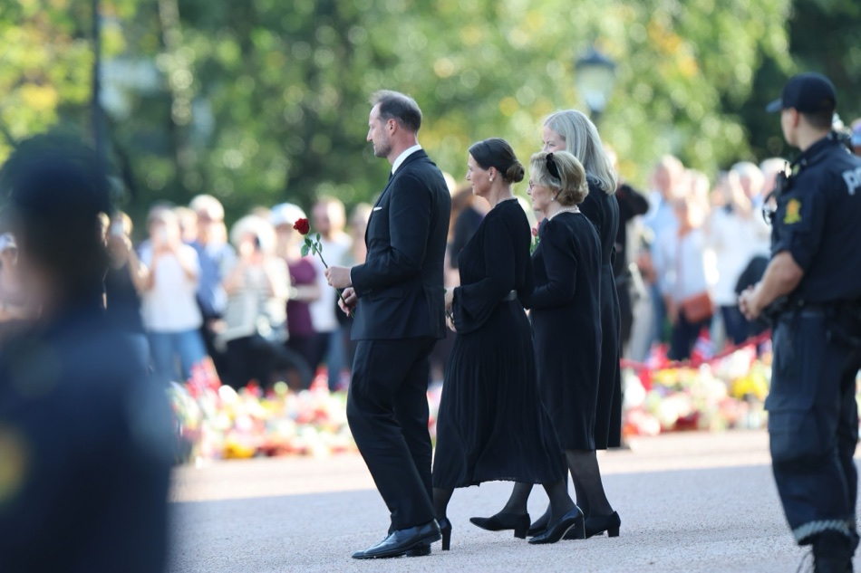 Kong Haakon med en rød rose i hånden går over Slottsplassen sammen med prinsesse Märtha Louise, dronning Sonja og dronning Mette-Marit
