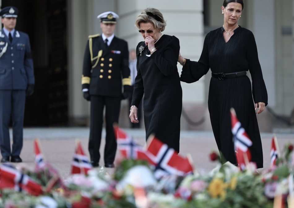 Dronning Sonja tørker øynene mens prinsesse Märtha Louise holder henne under armen foran blomsterhavet