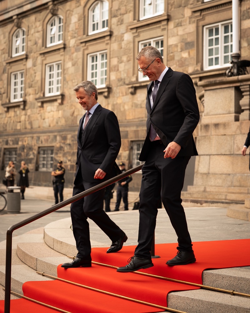 King Frederik walks down the red carpet on the steps outside Christiansborg