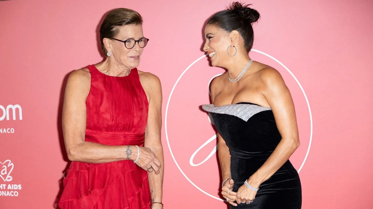 Princess Stéphanie and Eva Longoria laughing together in front of the wall with the Fight Aids Monaco logo