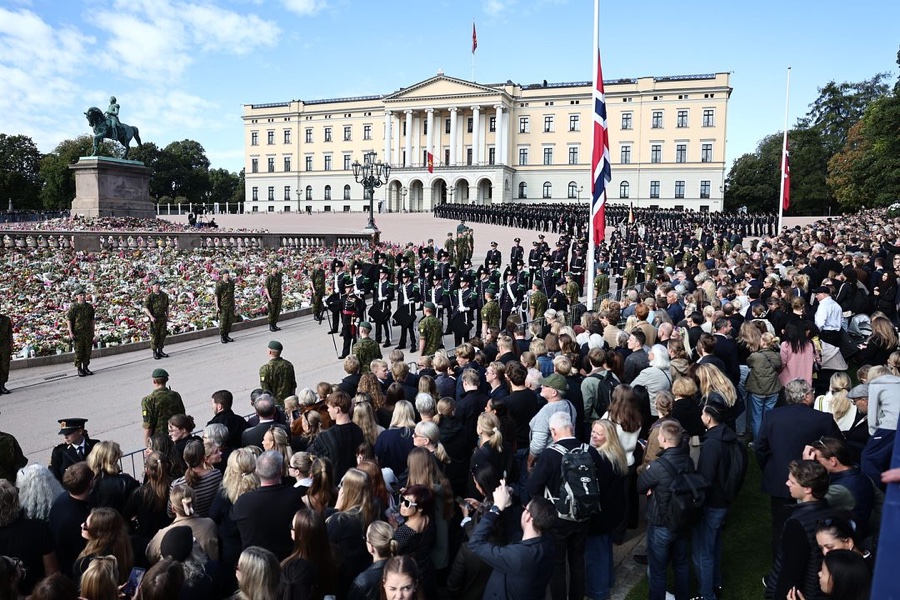 Crowds stand densely in front of the Palace and the sea of flowers, with guardsmen and a guard of honour drawn up on the Palace Square