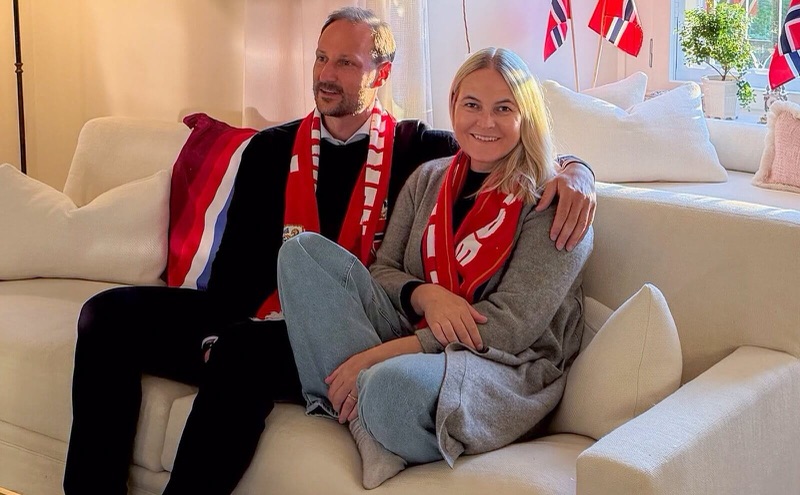 Kronprins Haakon og kronprinsesse Mette-Marit i sofaen med landslagsskjerf