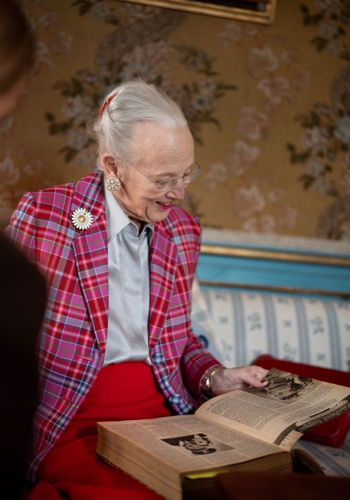 Queen Margrethe leaning over a spread in an old issue of Alt for damerne