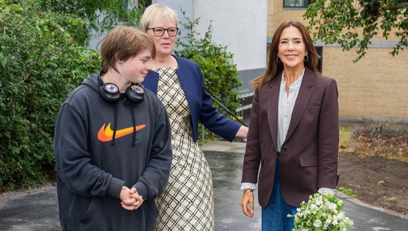 Dronning Mary med blomsterbukett sammen med en ung beboer