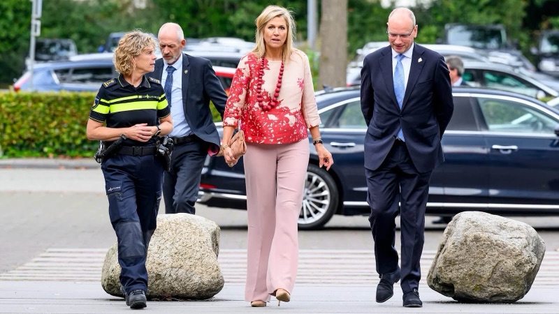 Dronning Máxima går mot inngangen sammen med en kvinnelig politisjef i uniform og en mann i mørk dress