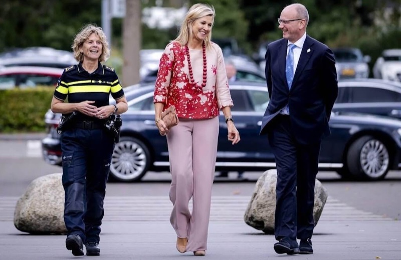 Dronning Máxima ler sammen med politidirektøren og en mann i dress på vei inn til besøket