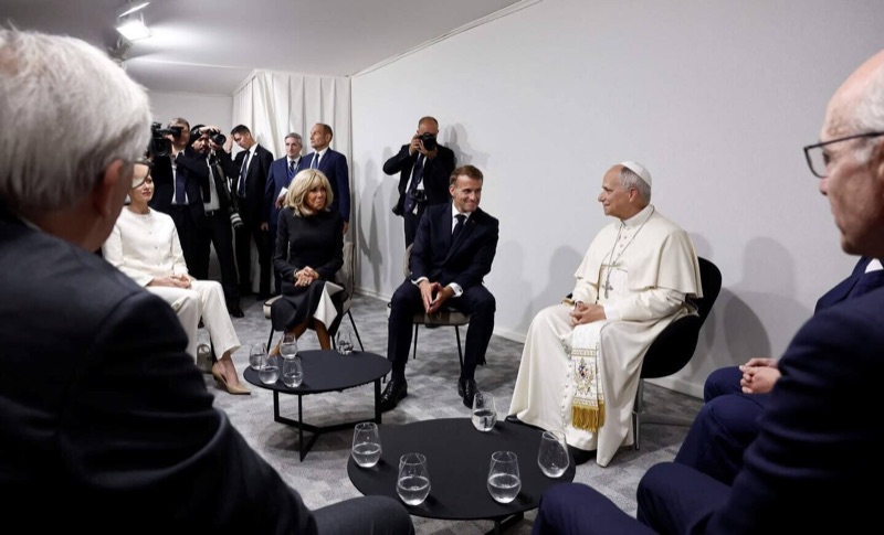 Pave Leo XIV sitter i hvit drakt overfor Emmanuel Macron, Brigitte Macron og fyrstinne Charlène i et møterom