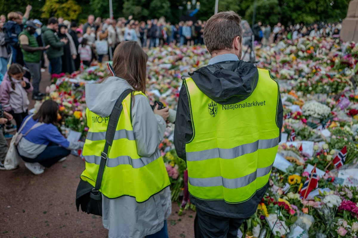Two National Archives staff in high-visibility vests standing in front of the sea of flowers on the Palace Square
