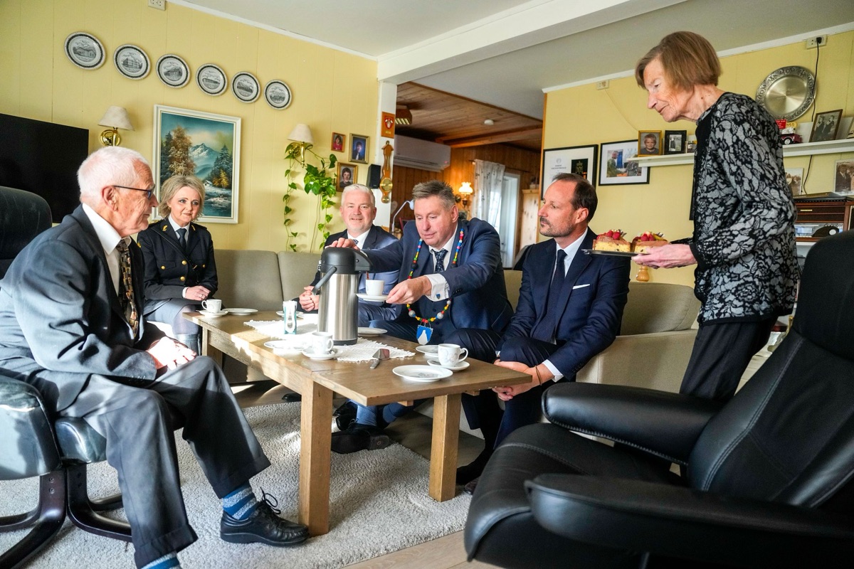 Kong Haakon sitter rundt stuebordet hjemme hos Magne Øymo