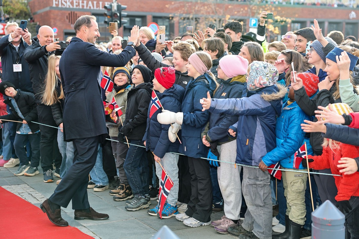 Kong Haakon gir high five til barn og voksne bak sperringene