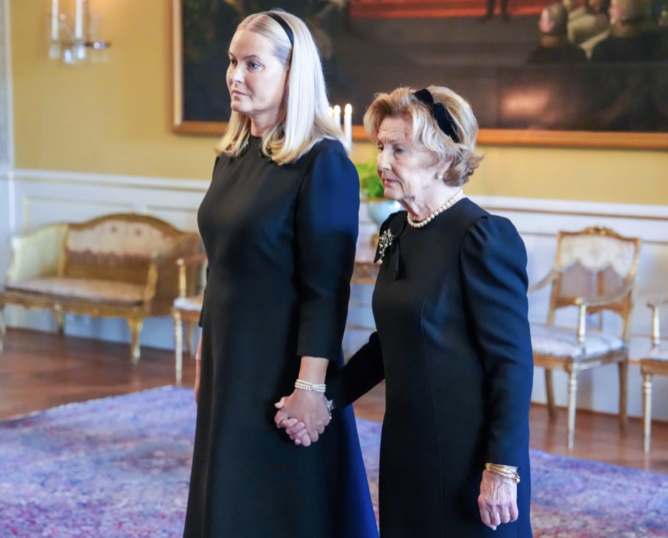 Dronning Mette-Marit og dronning Sonja går hånd i hånd gjennom en av salene på Slottet