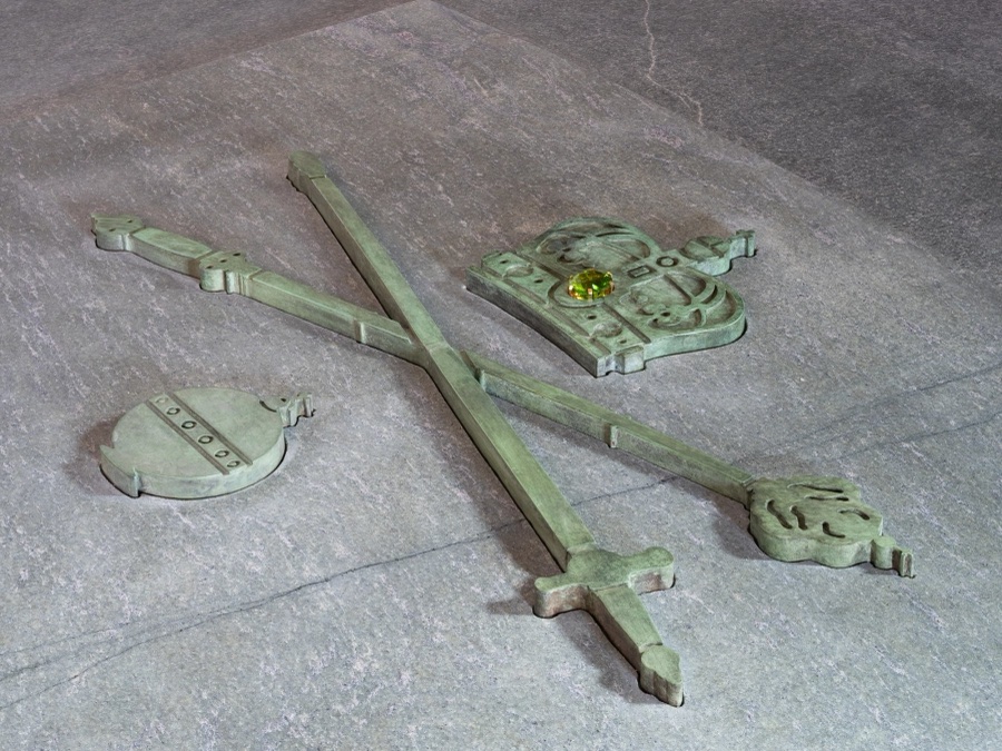 The royal crown, the sword of state, the sceptre and the orb rendered in bronze, partly recessed into the stone lid