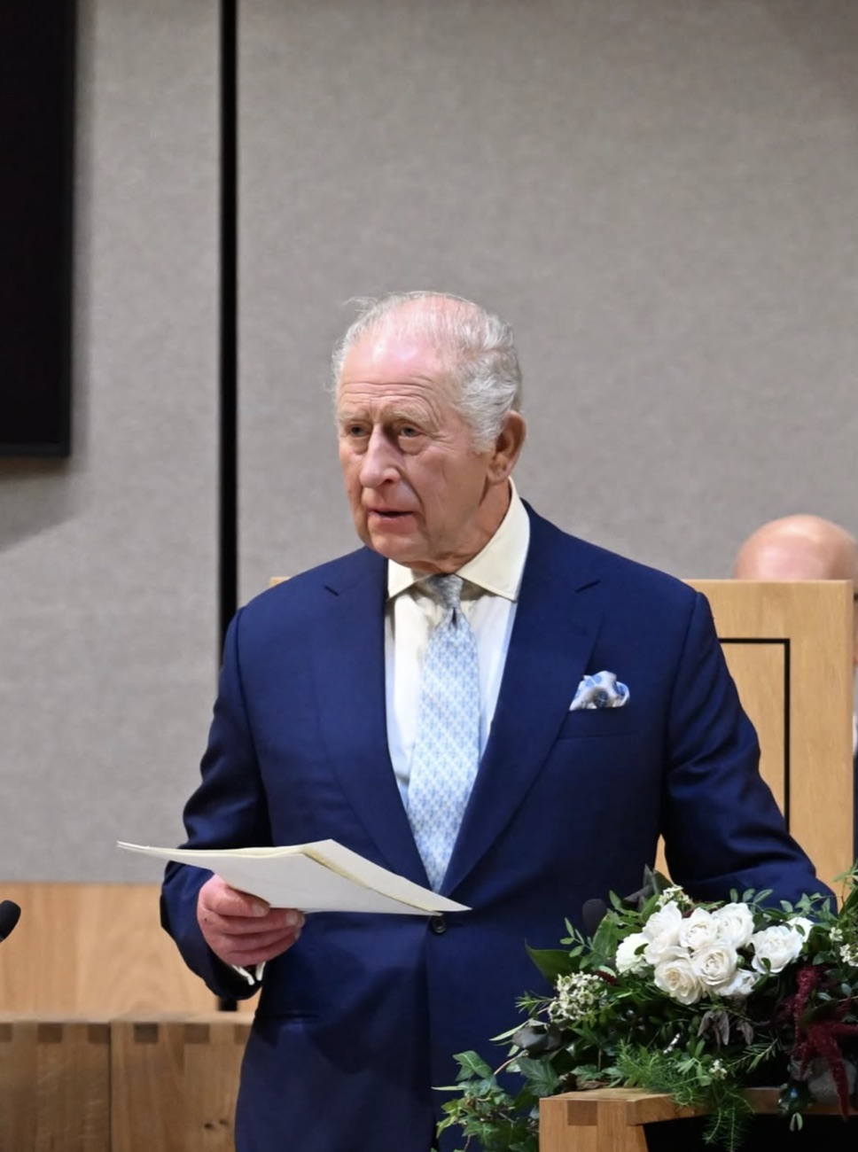 Kong Charles står med talepapirene i hånden i salen