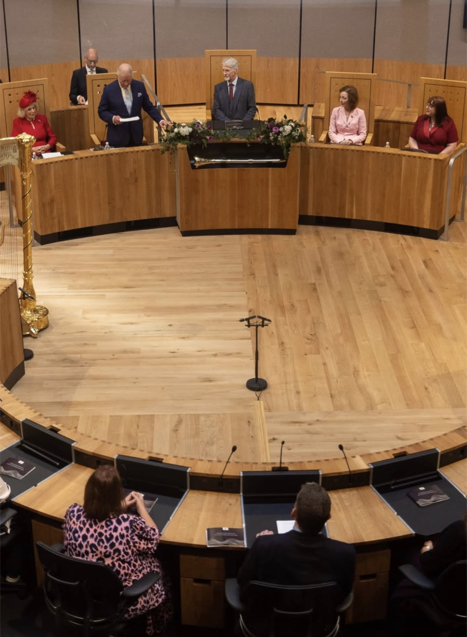 Oversiktsbilde av den runde debattsalen i Senedd med folkevalgte på plassene sine