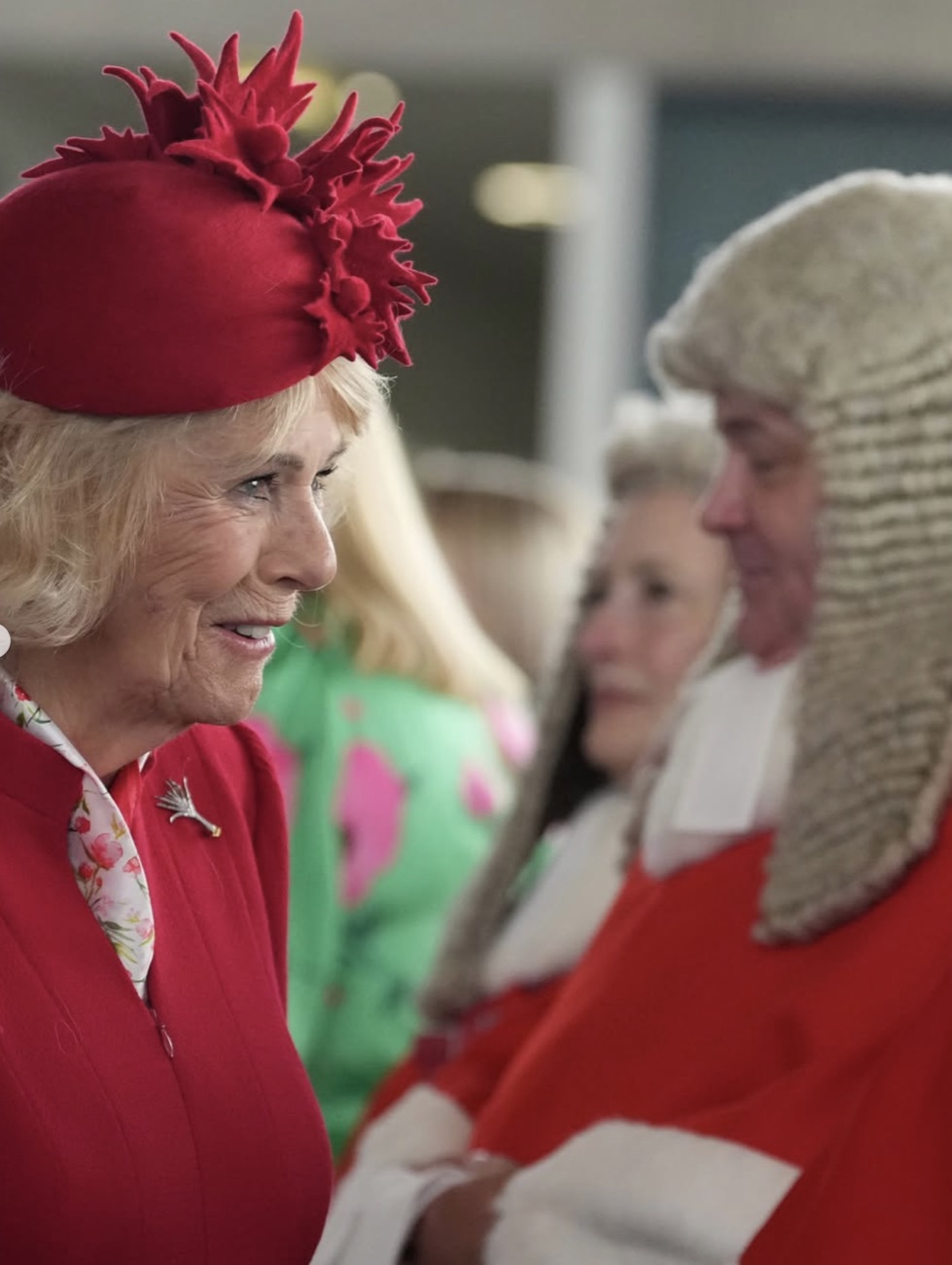 Dronning Camilla smiler i samtale med en dommer i parykk