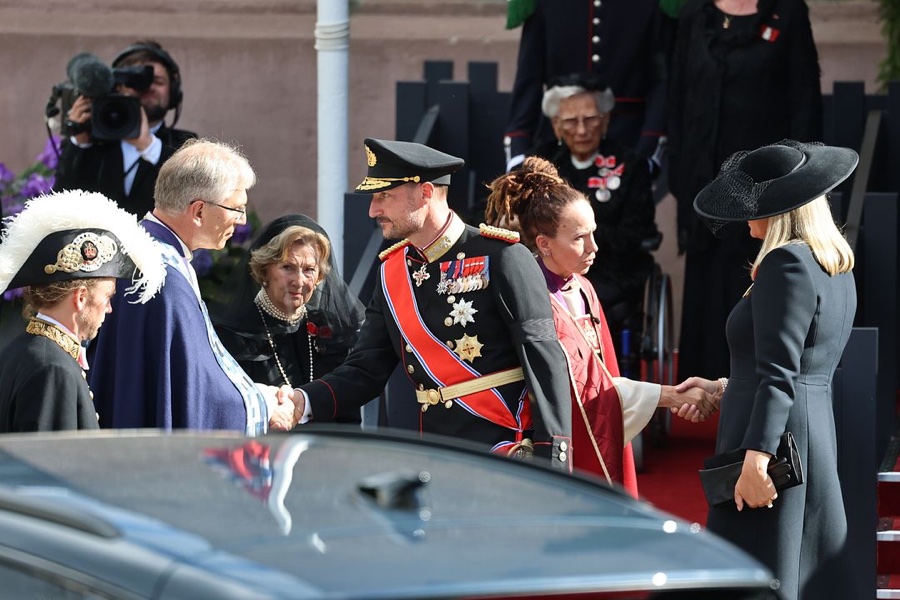 King Haakon in full dress uniform shakes hands outside the cathedral, with Queen Sonja and Queen Mette-Marit beside him