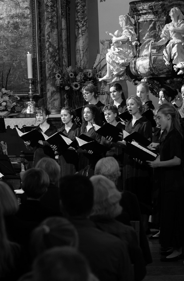 Singers from the Fredensborg Palace Chapel Girls Choir singing with scores in their hands in front of the altar