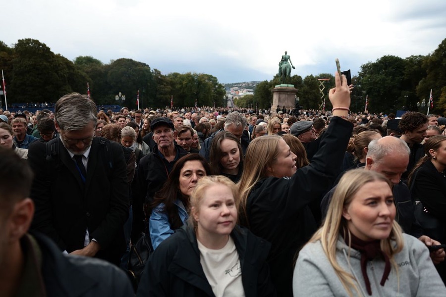 A dense crowd on the Palace Square, one person holding up a phone to film