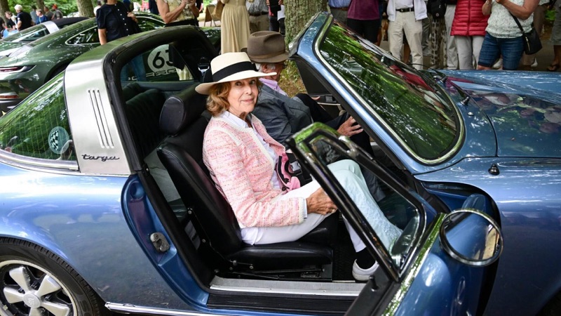 Dronning Silvia sitter i en blå Porsche med kongen ved siden av