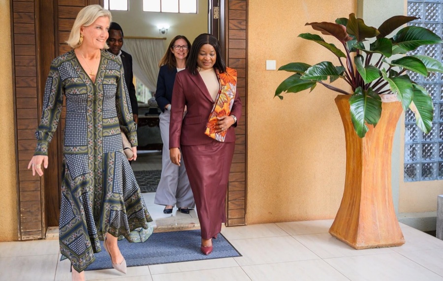 The Duchess of Edinburgh in a patterned dress walks through a doorway alongside Mutinta Hichilema in a burgundy suit