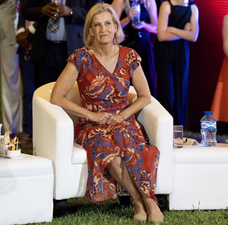 The Duchess of Edinburgh sits in a white armchair outdoors on the grass