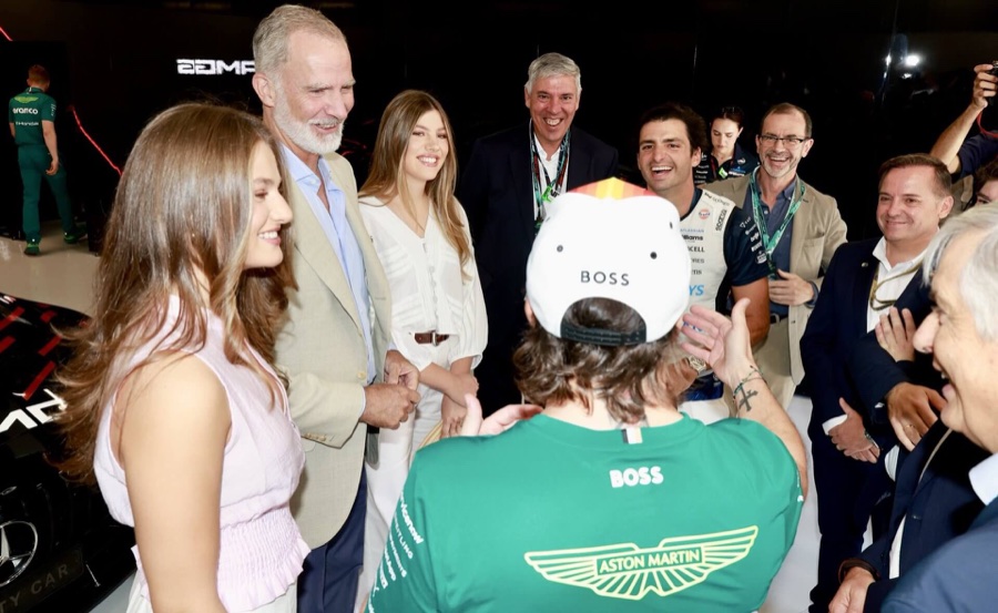 The King and his daughters laugh with drivers and team members inside the garage