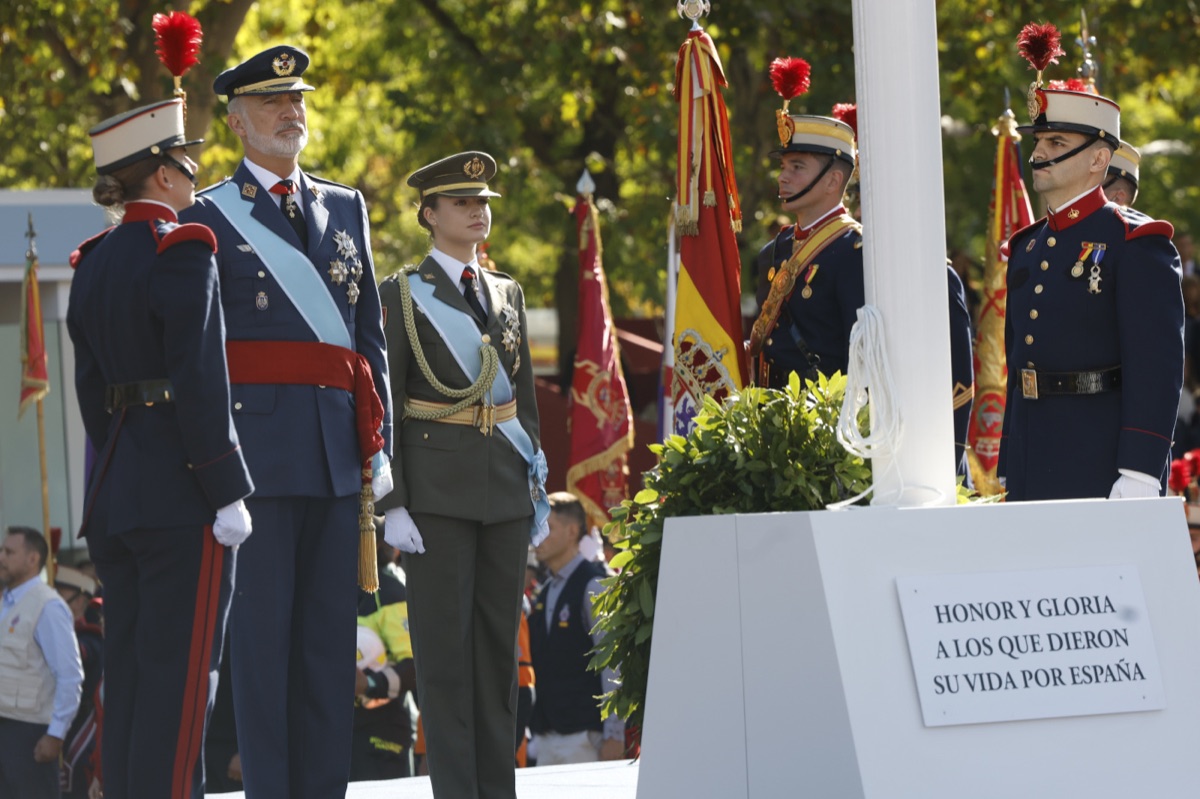 King Felipe in air force uniform and Princess Leonor in army uniform standing at the memorial to the fallen