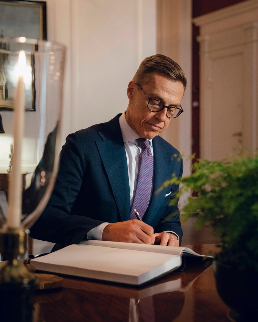 President Alexander Stubb writing in a large book at a table in the Ministers